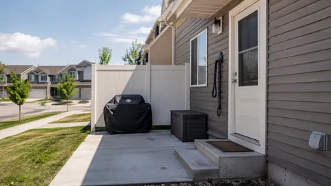 A small enclosed townhouse patio with a grill and storage box, standing in for a private yard, with a leash hanging by the back door
